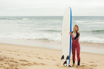 Fototapeta na wymiar Smiling female surfer with surf longboard board near ocean