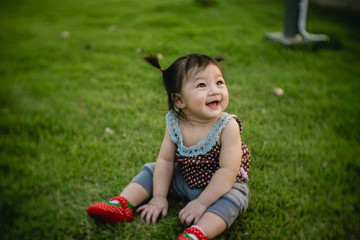 Smile asian baby girl playing on the grass.