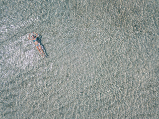 Young woman swimming in transparent sea water, drone aerial view. Gili islands, Indonesia