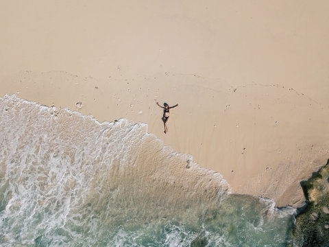 Woman relaxing on sea beach, Nusa Penida Island in Indonesia. Drone aerial view