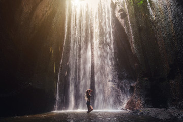 Woman enjoying in tropical waterfall
