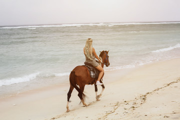 Woman wearing braids hairstyle riding horse on sea shore