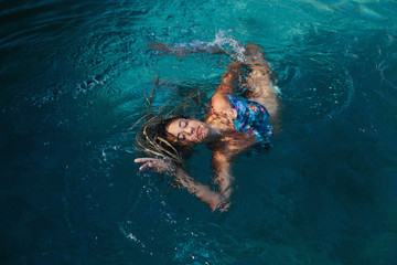 Woman swimming relaxing in tropical swimming pool outdoor. Summer sunny  day