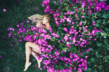 Obraz na płótnie Canvas Beautiful female sleeping outdoor in nature under bougainvillea flowers