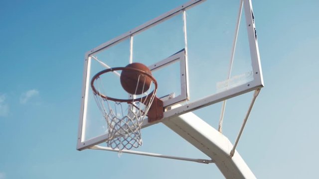Male basketball player runs up to hoop and scores in slow motion SHORT CLIP