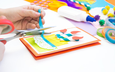 Child makes a postcard with a picture of a cake. Kid paperwork.