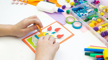 Child makes a postcard with a picture of a cake. Kid paperwork.