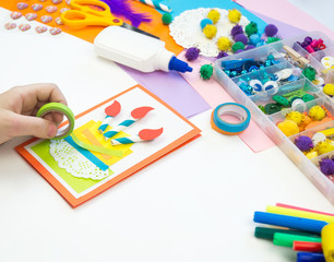 Child makes a postcard with a picture of a cake. Kid paperwork.