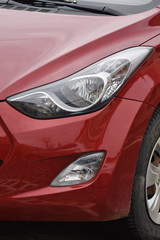Obraz na płótnie Canvas Car's exterior details. shiny headlights on a red car