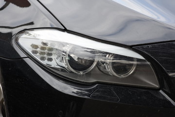 Fototapeta na wymiar Car'sCar exterior detail.shiny headlight on a black car exterior detail, headlight on a new car