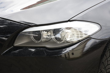 Obraz na płótnie Canvas Car'sCar exterior detail.shiny headlight on a black car exterior detail, headlight on a new car