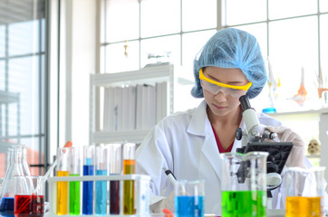 The woman scientist in laboratory doing experiments with microscope.