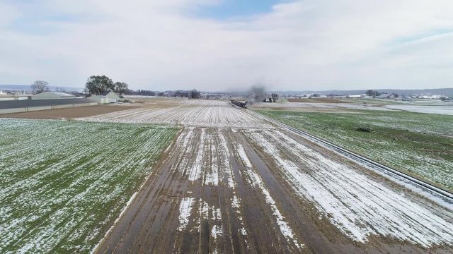 Ariel View of Thomas the Train and Passenger Cars Puffing Smoke Along Amish Farm Lands After the First Snow of the Season