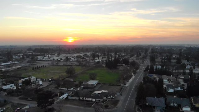Aerial shot panning up from a car driving towards a sunset in the distance in 4K