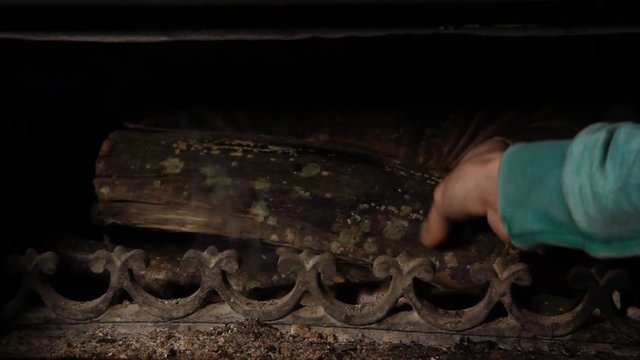 Man hand putting wood on the fire in the fire place.