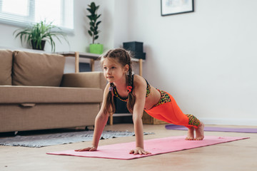 Little girl doing plank exercise at home.