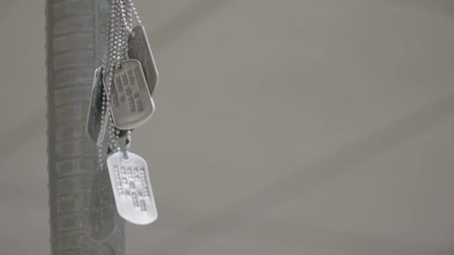 Military dog tags blowing in the wind at a memorial in slow motion.