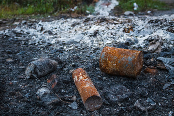 The rusty burned-down metal tins lie in ashes