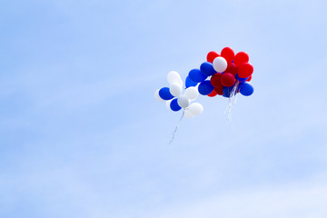 Multicolored balloons fly in the blue sky.