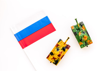 War, military threat, military power concept. Russia. Tanks toy near russian flag on white...