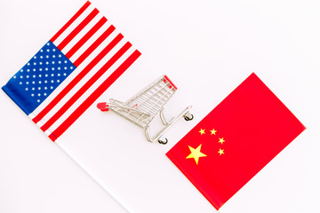 USA and China trade war. American and chinese flags near shopping chart on white background top view space for text