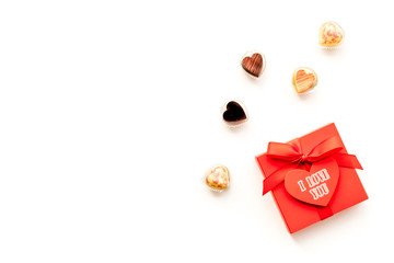 Gift for Valentine's day. Gift box with text I love you and heart-shaped sweets on white background top view copy space