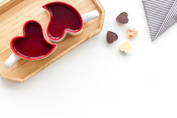 Valentine's day concept. Heart-shaped mugs and sweets on white background top view copy space