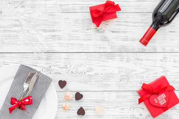 Valentine's day dinner concept. Decorated dishes, tableware, wine, gift box on white wooden background top view copy space