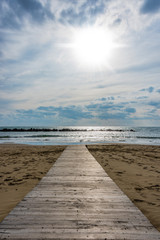 Fototapeta na wymiar Wooden Walkway on an Italian Beach Out to the Mediterranean Sea
