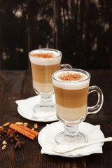 Coffee in glass on the wooden background.  A glass with cappuccino and cinnamon. 