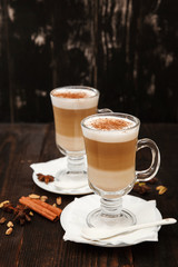 Coffee in glass on the wooden background.  A glass with cappuccino and cinnamon. 