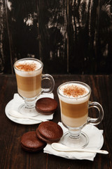 Coffee in glass on the wooden background.  A glass with cappuccino and cinnamon. 