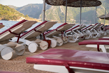 Landscape with sun beds and umbrellas in the foreground and the sea with mountains in the background