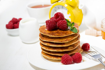 stack of pancakes with fresh raspberries for breakfast on white table, closeup