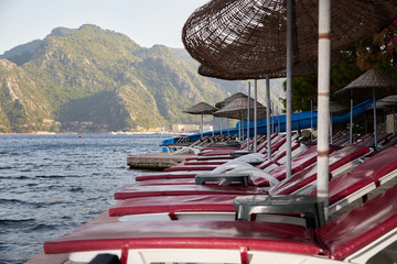 Landscape with sun beds and umbrellas in the foreground and the sea with mountains in the background