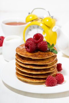 stack of pancakes with fresh raspberries for breakfast on white table, vertical