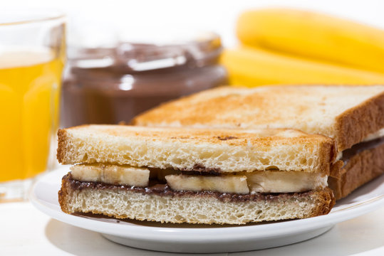 sweet sandwich with chocolate paste and banana on white table