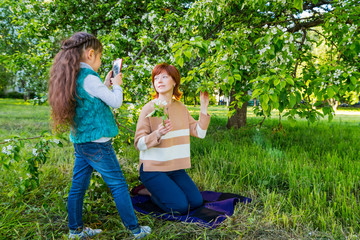 Mother and daughter having fun near blossom apple trees