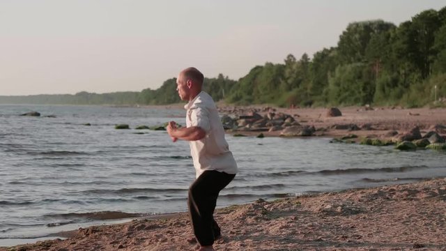 Martial artist monk practicing routine on the beach.