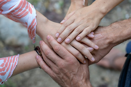 Many hands getting together in the center of a circle. Close up outdoor shot