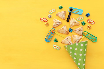 Purim celebration concept (jewish carnival holiday) over wooden yellow background.