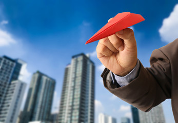Business man in suit holding red paper airplane
