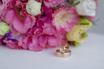 Gold wedding rings lie on a bouquet for the bride. Wedding accessories