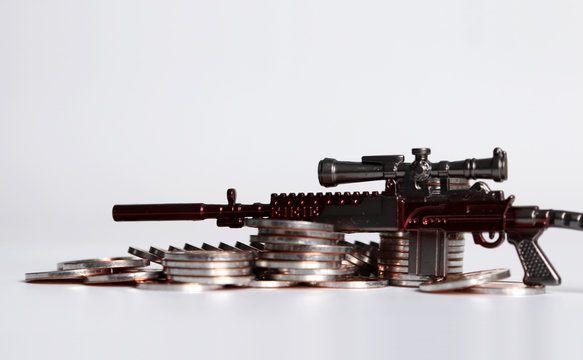 A miniature gun on a pile of coins.