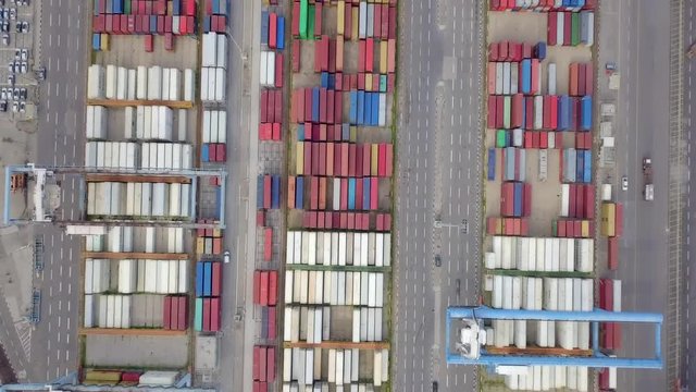 Transtainer yard - Various brands and colours of Shipping containers stacked by Transtainers (Mobile gantry cranes) off of service trucks - Top down aerial footage.