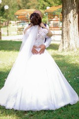 Fototapeta premium Hands of the groom in the form of a heart on the waist of the bride