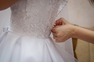 Woman laces up corset on bride's  waist. Morning bride concept