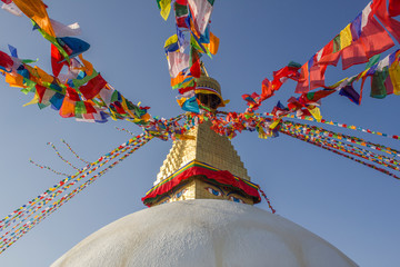Tibetan Buddhist colored prayer flags on the Bodnath Temple stupa on the background of clean blue...
