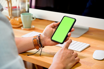 Man hand holding blank screen mobile smart phone on desk in office