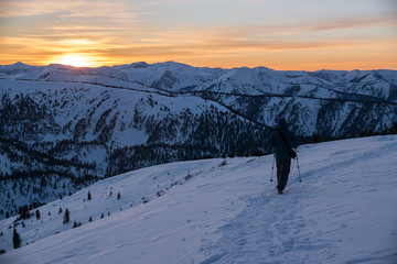 A tourist walks along a mountain range at sunset